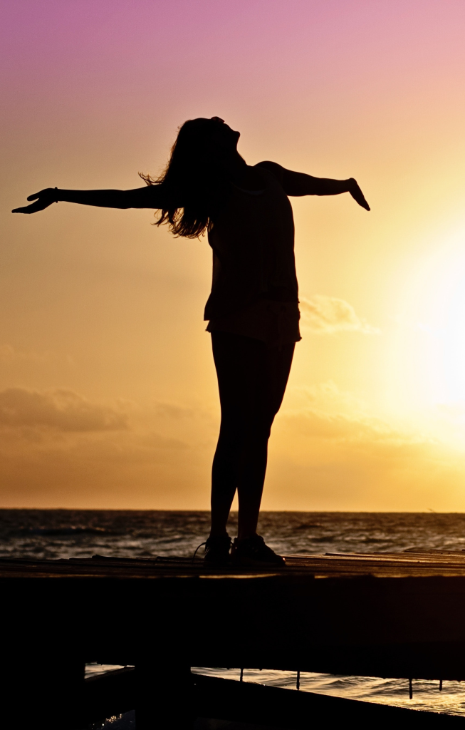 Femme bras ouvert dans une porte sur coucher de soleil, symbolisant une thérapie psycho-corporelles